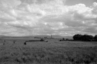 farmland with a building in the distance with a chimney stack