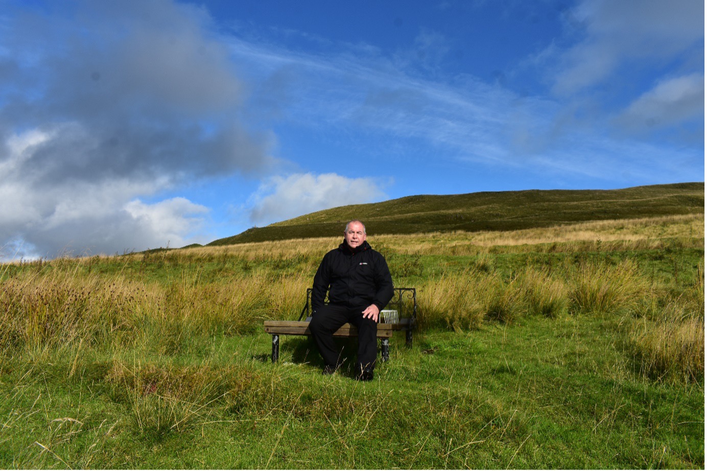 Man sitting on a bench on a hillside 