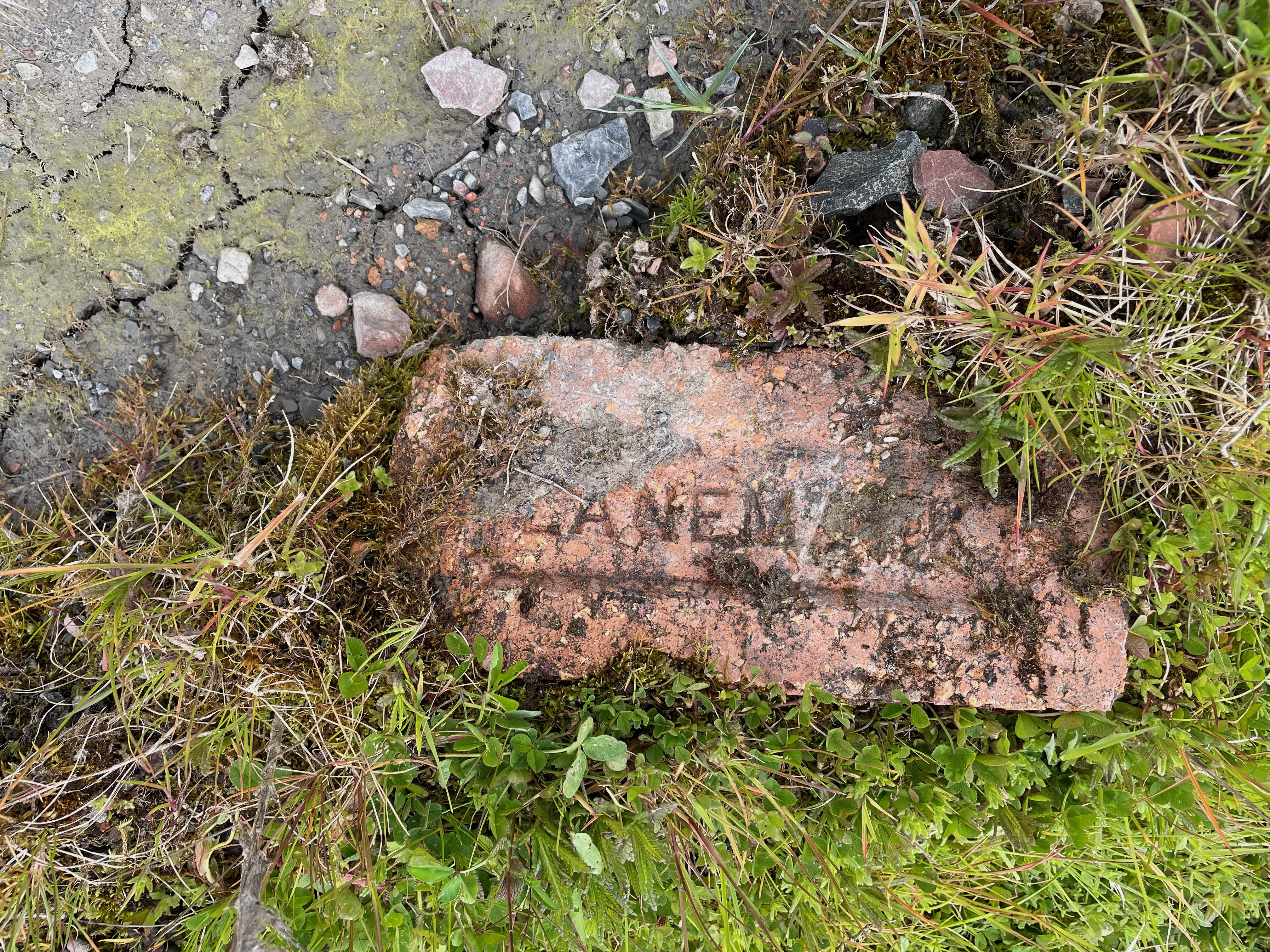 A red brick lying embedded in the ground. 