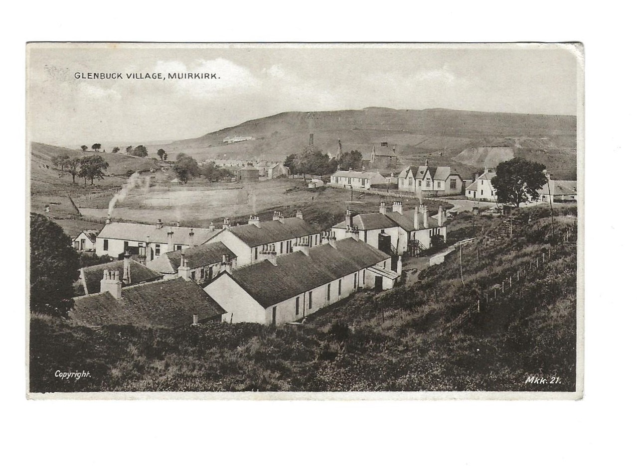 postcard with black and white photograph showing a village with white houses surrounded by hills.