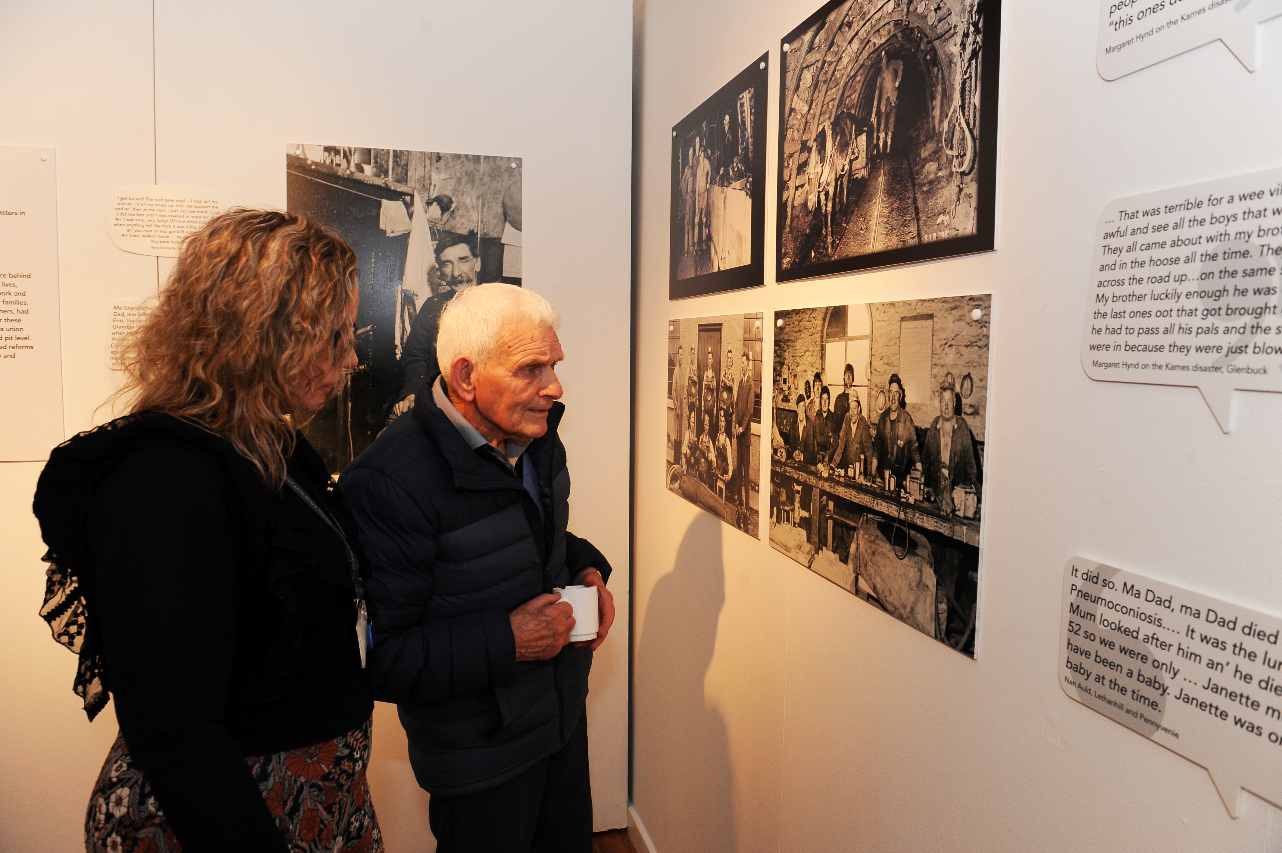 Man and woman looking at photos on wall